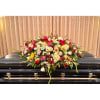 Large floral spray on a black casket with red, pink, and white blooms