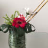 Red gerbera focal bloom with white daisy, green fillers and dark leaves