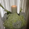 White floral arrangement with a lit pillar candle and calla lilies