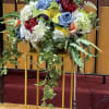 Large floral arrangement with multicolored blooms and trailing greenery on a stand