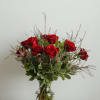 Red roses arranged in a clear glass vase with greenery