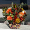 Orange roses and mixed fall flowers in a decorative floral box