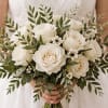 A timeless hand-tied bridal bouquet featuring creamy white roses, delicate white accents