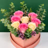 Pink and cream roses arranged in a heart-shaped box