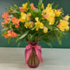 Bouquet of yellow and coral alstroemeria in a pink glass vase with a ribbon
