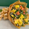 Bouquet of yellow and coral alstroemeria wrapped in gold paper with a ribbon