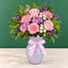 Pink roses and mixed flowers in a lavender vase with a pink ribbon