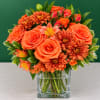 Orange roses and chrysanthemums in a clear square vase