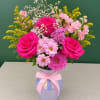 Pink roses and mixed blooms in a blue vase with a pink ribbon