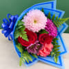 Bouquet of red roses, pink chrysanthemums, and carnations wrapped in blue paper