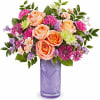 Peach roses and pink flowers in a purple glass vase