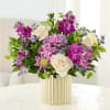 Bouquet of white roses, pink flowers, and purple blooms in a striped gold vase