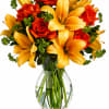 Orange roses and yellow lilies in a clear glass vase