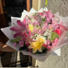 Pink and yellow mixed flower bouquet wrapped in white paper