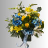 Bouquet of yellow, blue, and white flowers in a dark vase with a blue ribbon