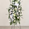 Tall white floral standing spray on an easel with ribbon accents