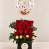 Red roses in a black box with a clear confetti balloon above