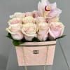 Pink roses and an orchid arranged in a quilted pink handbag-style box