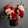 Red and blush roses arranged in a burgundy hat box