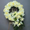 White and pale yellow floral funeral wreath on a wooden easel