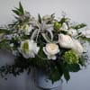 White floral arrangement in a vase with green accents and curled ribbon loops