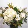 White hydrangeas and roses in a glass vase with mixed greenery