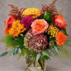 Colorful bouquet of roses, chrysanthemums, hydrangea, and marigolds in a glass vase