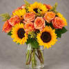 Bouquet of orange roses and yellow sunflowers in a clear glass vase