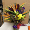 Tropical bouquet with orange bird-of-paradise and yellow lilies in a glass vase
