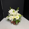 White rose and lily bouquet in a low container with a brown ribbon