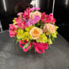 Mixed bouquet of peach roses, pink flowers, and yellow alstroemeria in a glass vase