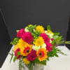 Mixed bouquet of pink roses and yellow-orange gerbera daisies in a glass vase