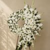 White floral funeral wreath on a stand with daisies and lilies