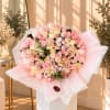 Large bouquet of pastel pink and cream roses wrapped in lace-edged paper