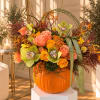 Floral arrangement in a pumpkin container with roses and orchids