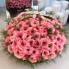 Round basket of pink carnations with ribbon handle
