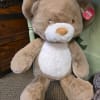 Large brown and white plush teddy bear sitting on the floor