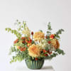 Orange and yellow mixed flower arrangement in a green ceramic vase
