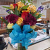 Mixed bouquet of roses, sunflowers, and chrysanthemums with a large blue ribbon