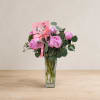 Pink peony bouquet in a clear glass vase with a ribbon and card