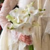 Bride holding a white orchid bouquet against a lace wedding dress