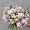 Handheld bouquet of pale pink, white, and lavender flowers