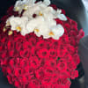 Red rose arrangement topped with white orchids in a black container