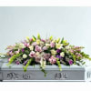 Pastel floral casket spray with roses and lilies on a silver casket