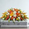 Orange, yellow, and white floral spray on a silver casket