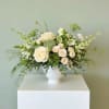 White rose arrangement in a white vase with airy greenery