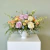Pastel rose arrangement in a white pedestal vase