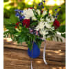 Red roses and white daisies in a blue vase with ribbon