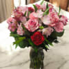 Pink roses and alstroemeria in a clear glass vase with a red carnation