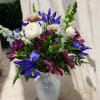 Mixed bouquet of white, purple, and pink flowers in a white vase